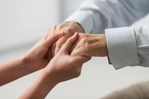 The hands of a young and elderly person symbolizing support and care.
